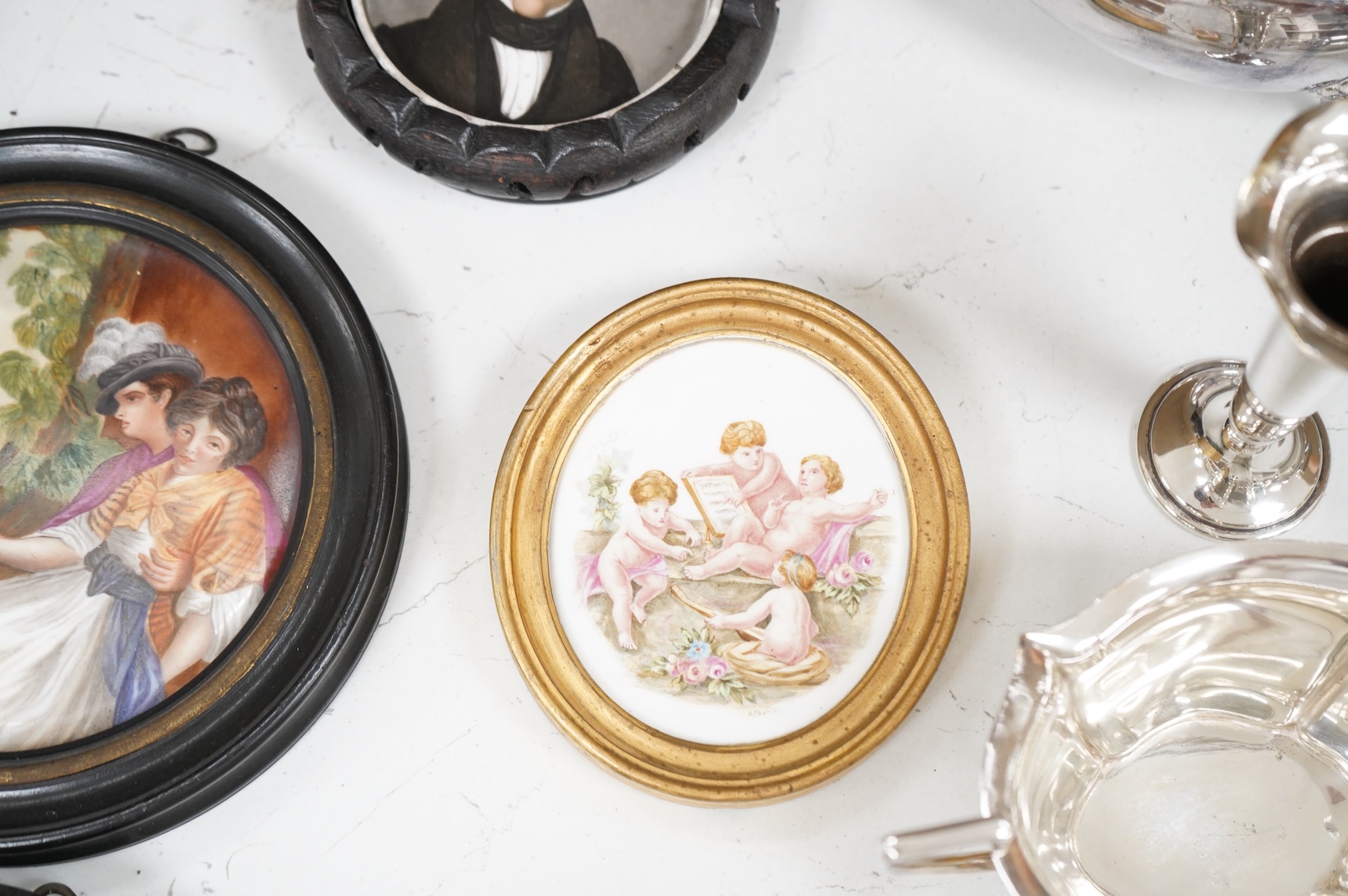A collection of 19th century porcelain panels, pot lids and plaques to include a pair of hand painted floral lids, Russian lacquered box depicting a lady and a late 19th century Continental brass framed convex oval ename